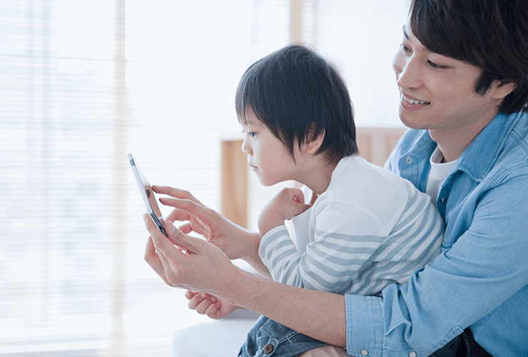 父親が息子を抱えてスマートフォンの画面を見せている写真